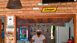 Un bar con pared de ladrillo, un refrigerador de Coca-Cola y un cartel que dice "Schweppes".