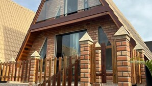 Una casa moderna con techo triangular, paredes de ladrillo y cerca de madera.
