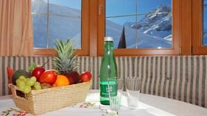 A table with a fruit basket, a bottle, and glasses. - Alpenhotel Seiler (Silz)