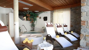 A spa area with a hot tub, lounge chairs, and a table with towels and fruit. - Alpenhotel Seiler (Silz)