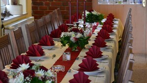 A long dining table set with red napkins, white plates, and floral centerpieces. - Landhaus Bondzio (Langen Brütz)