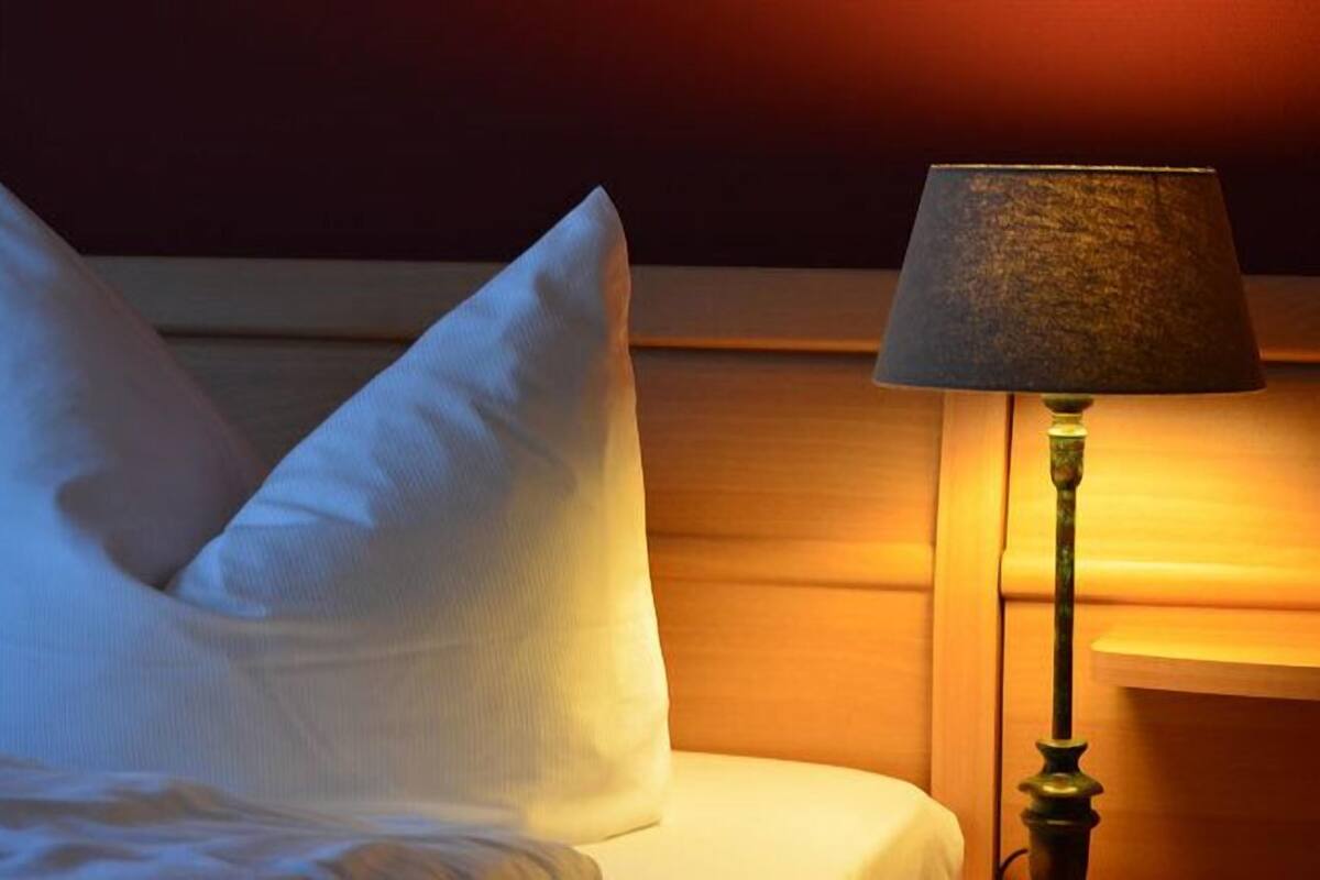 Una habitación de hotel con cama, almohadas y lámpara.