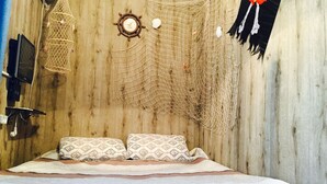 A room with a bed, a wall clock, a television, and a net hanging on the wall. - Alma Cinema Hostel (Almaty)