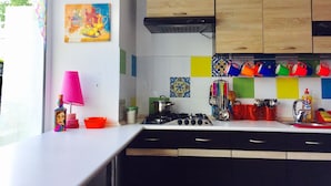 A kitchen with wooden cabinets, a gas stove, and colorful tiles. - Alma Cinema Hostel (Almaty)
