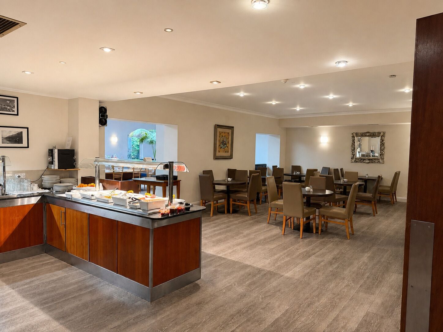 Comedor de hotel con barra de buffet, varias mesas y sillas.