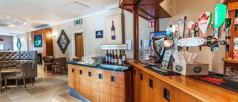 A bar area with a wooden counter, multiple beer taps, and a sign reading "FINE WINES BY THE GLASS".