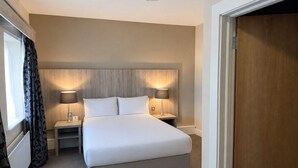 A hotel room with a large bed, two bedside tables, and a wooden headboard. - Wilton Hotel Bray (Bray)