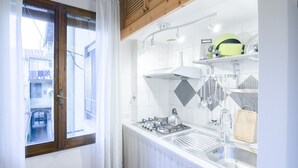 A modern kitchen with a gas stove, sink, and a window overlooking a residential area. - San Niccolò Loft by Mmega (Florence)