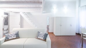 A modern living room with a white sofa, a staircase, and a white wardrobe. - San Niccolò Loft by Mmega (Florence)