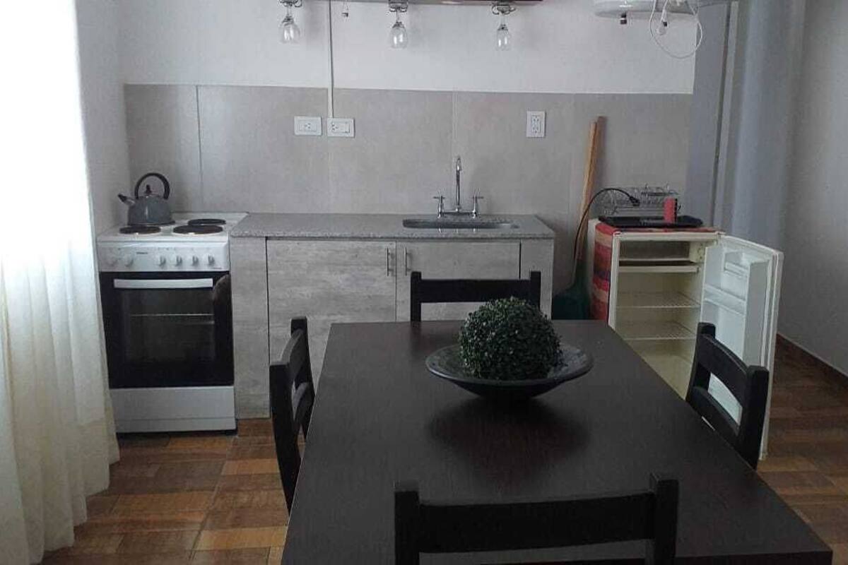 A compact kitchen with a stove, sink, and a dining table with chairs.
