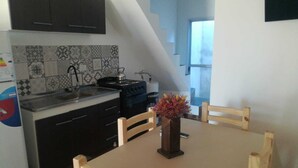 Une cuisine avec des meubles de couleur sombre, un pare-feu en carreaux, une cuisinière et une table à manger avec des chaises.