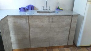 Une cuisine dotée d’un plan de travail en granit, d’un évier en acier inoxydable et de meubles en bois.