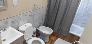 A bathroom with a toilet, bidet, sink, and bathtub. - Totoras Apart Federacion (Federacion)