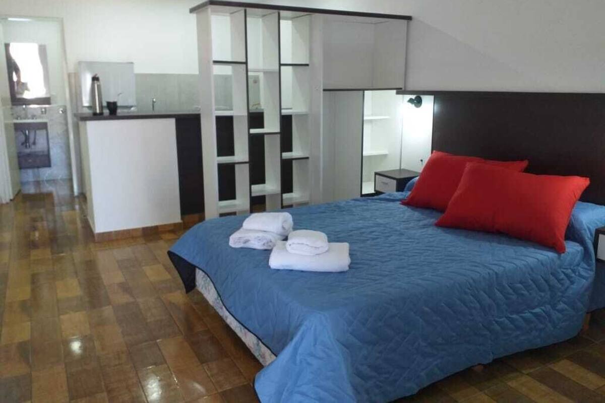 A bedroom with a large bed, a desk, and a mirror.