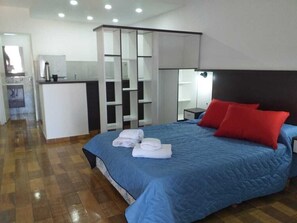 Un dormitorio con una cama grande, un escritorio y un espejo.