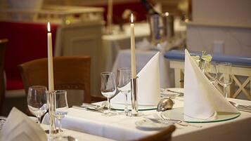 A dining table set with white tablecloth, candles, and glassware.