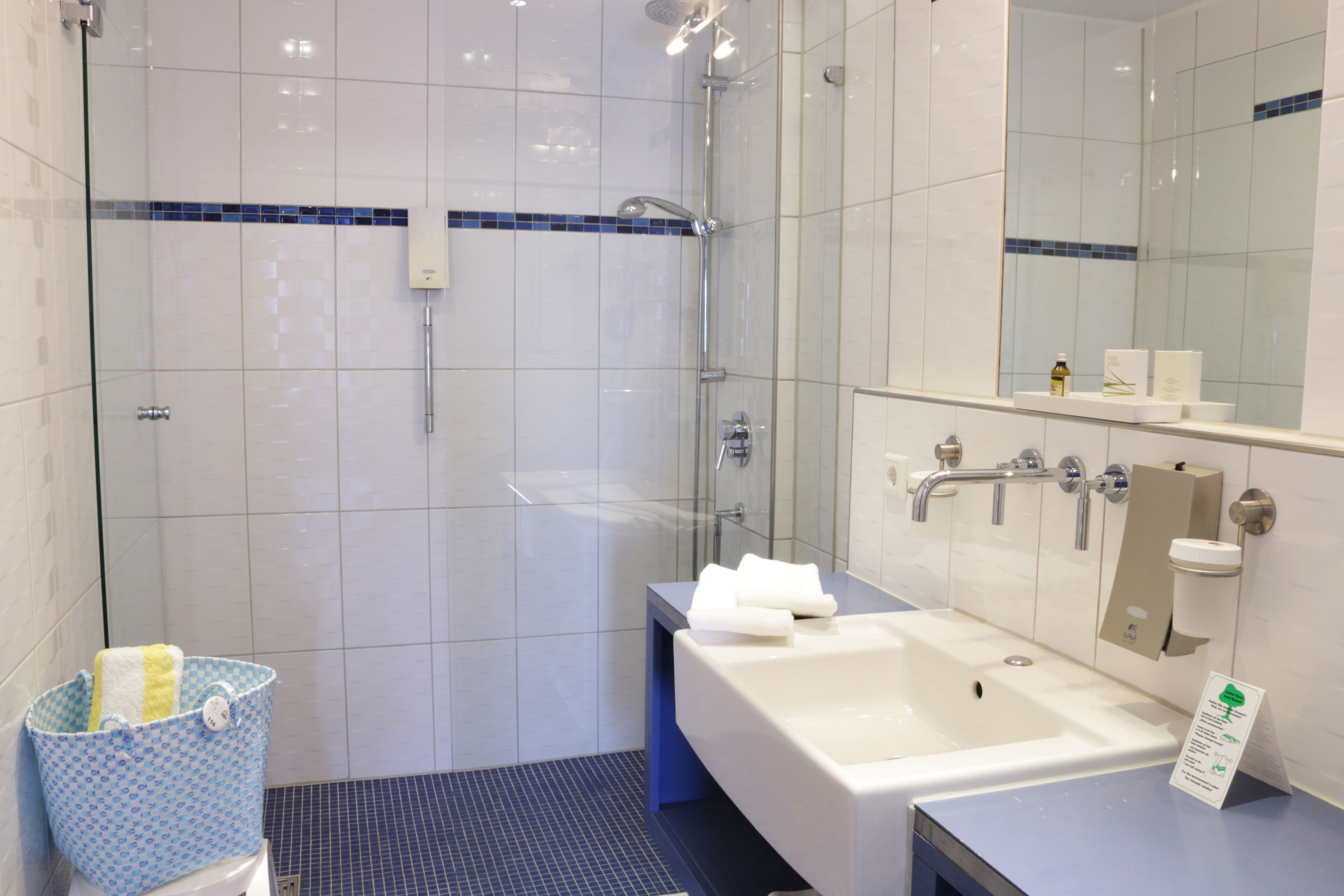 A modern bathroom with a glass-enclosed shower, a large white bathtub, and a sink with a mirror above.