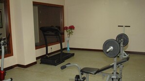 A home gym with a treadmill, bench press, and weight bench. - Paluri Hotel (Hopa)
