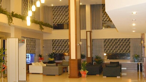 A spacious lobby with multiple seating areas, a central column, and hanging pendant lights. - Paluri Hotel (Hopa)