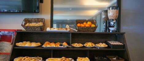 A buffet with various baked goods and fruits.