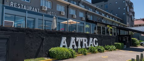 Un hôtel avec un restaurant au rez-de-chaussée, une façade noire et un ciel dégagé.