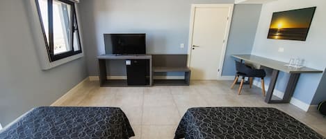 A room with two beds, a TV, a desk, and a chair.