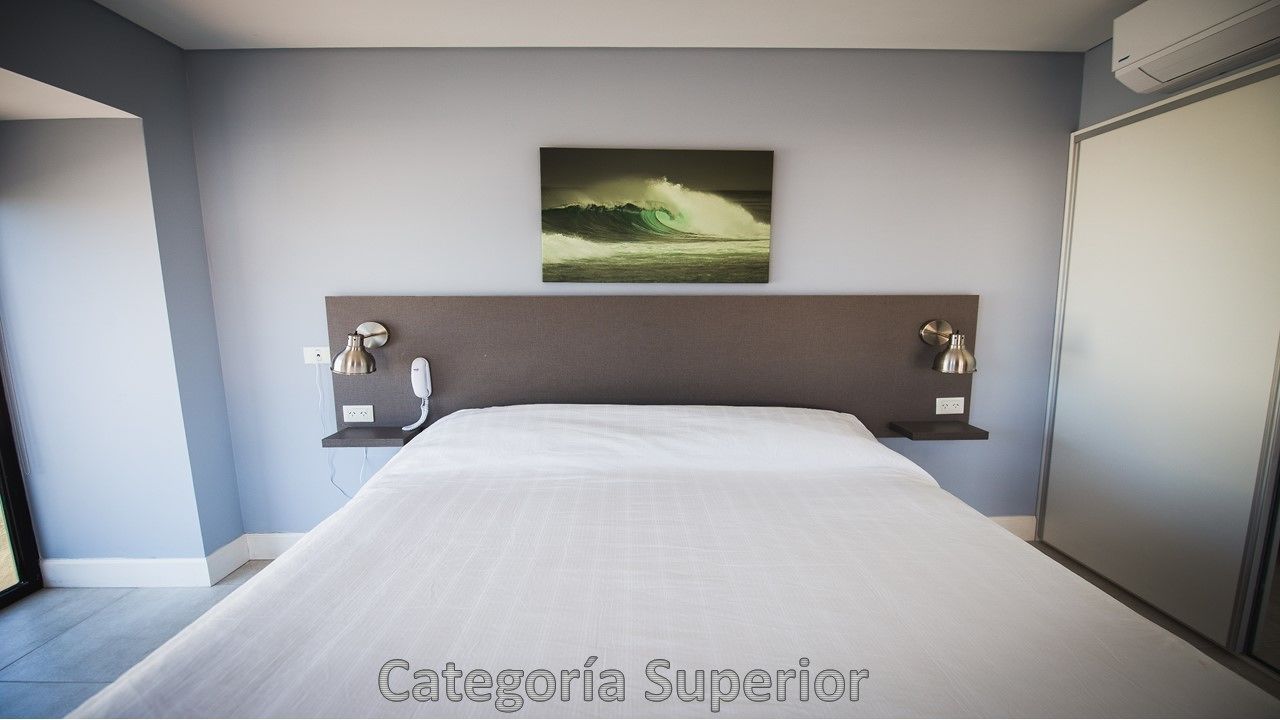 A modern hotel room with a large bed, a headboard with a painting, bedside lamps, and a wardrobe.