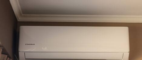 A white air conditioning unit mounted on a beige wall.