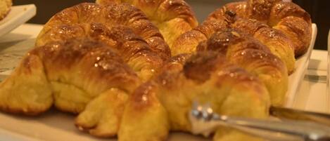 A plate of golden-brown croissants arranged on a white plate.