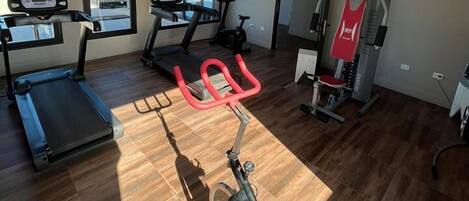 Un gimnasio en casa con cinta de correr, bicicleta estática y elíptica.