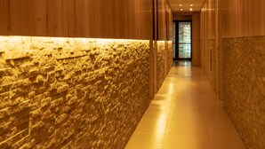 Un pasillo con paredes de madera y un detalle de pared de piedra, que conduce a una puerta al final.