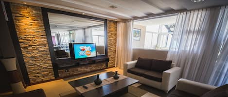 A modern living room with a stone accent wall, a flat-screen TV, a coffee table, and a sofa.
