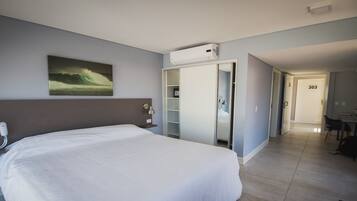 A hotel room with a large bed, a wardrobe, a desk, and a bathroom visible through an open door.