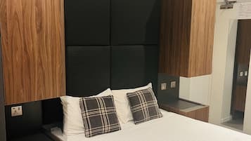 A hotel room with a bed, wooden headboard, two bedside tables, and a wardrobe.