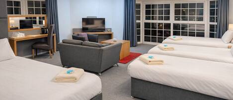 A hotel room with two beds, a desk, a television, and a sofa.
