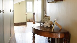 A hallway with a wooden floor, a wooden table with a picture frame and stuffed toy, and a wooden cabinet.