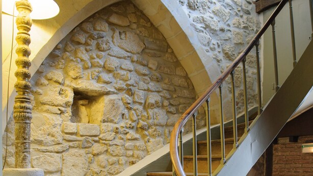 A spiral staircase with stone walls and a wooden handrail.