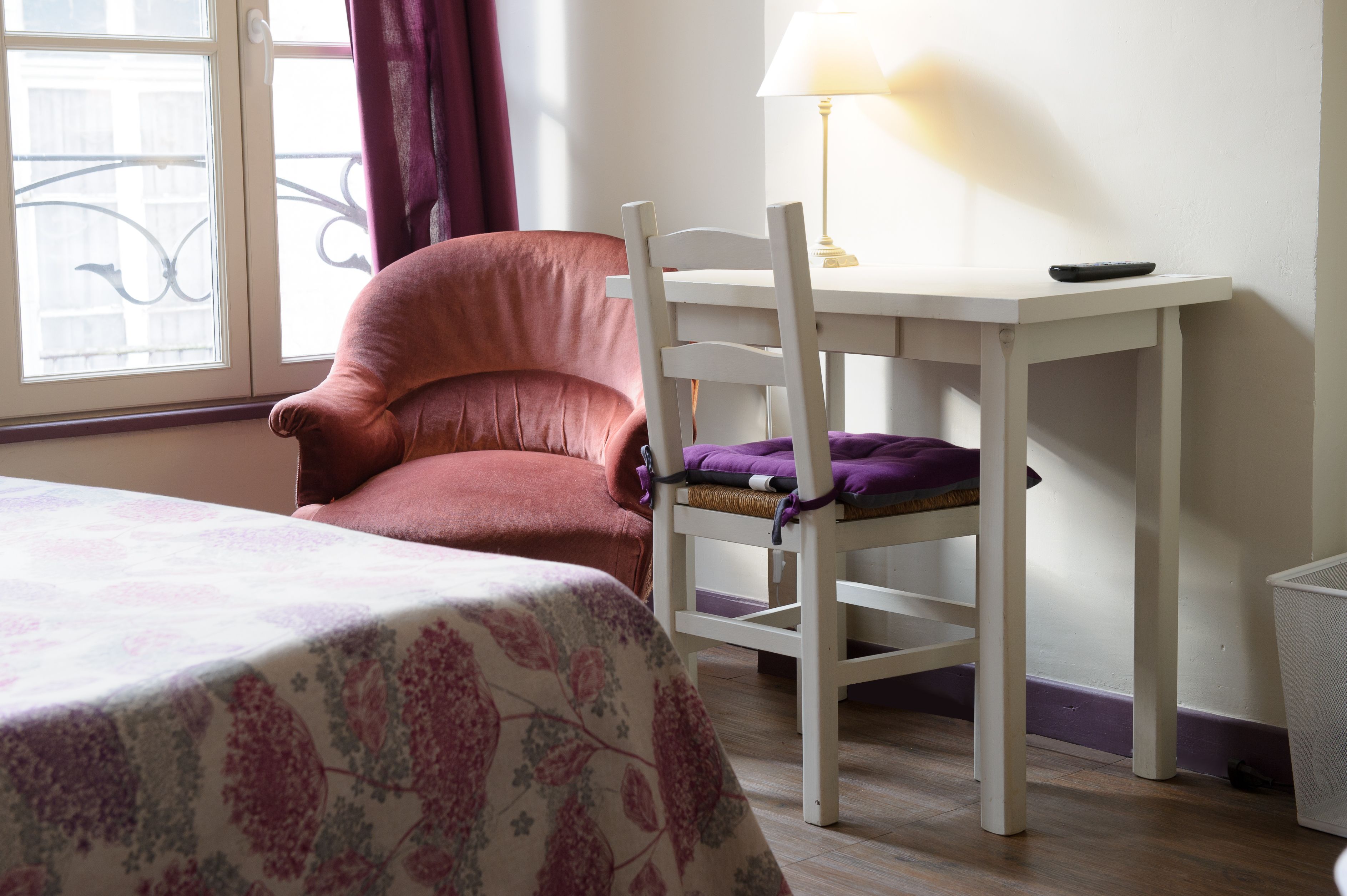 Una habitación con cama, una silla, una mesa y una lámpara.