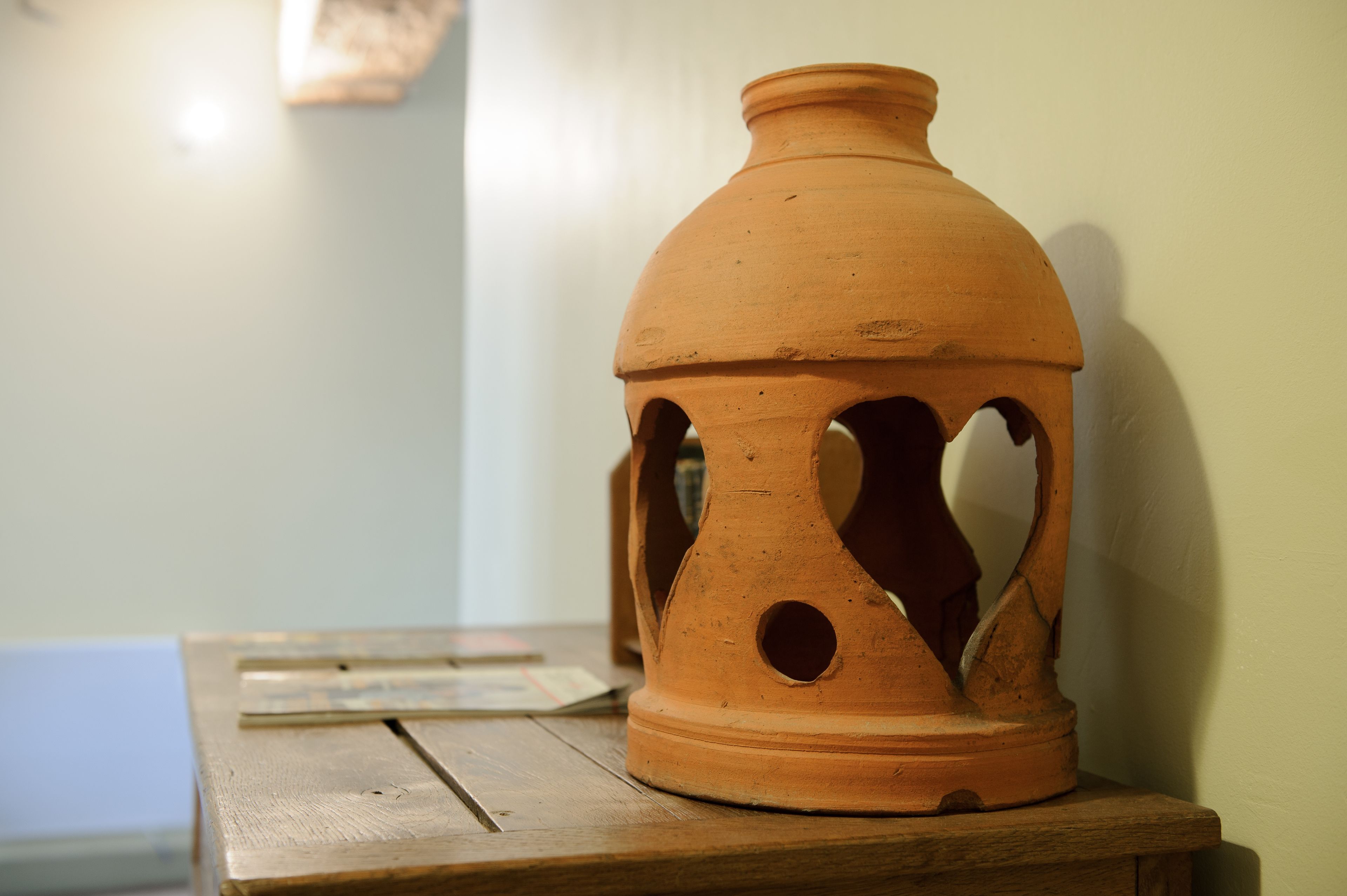A terracotta lantern on a wooden table.