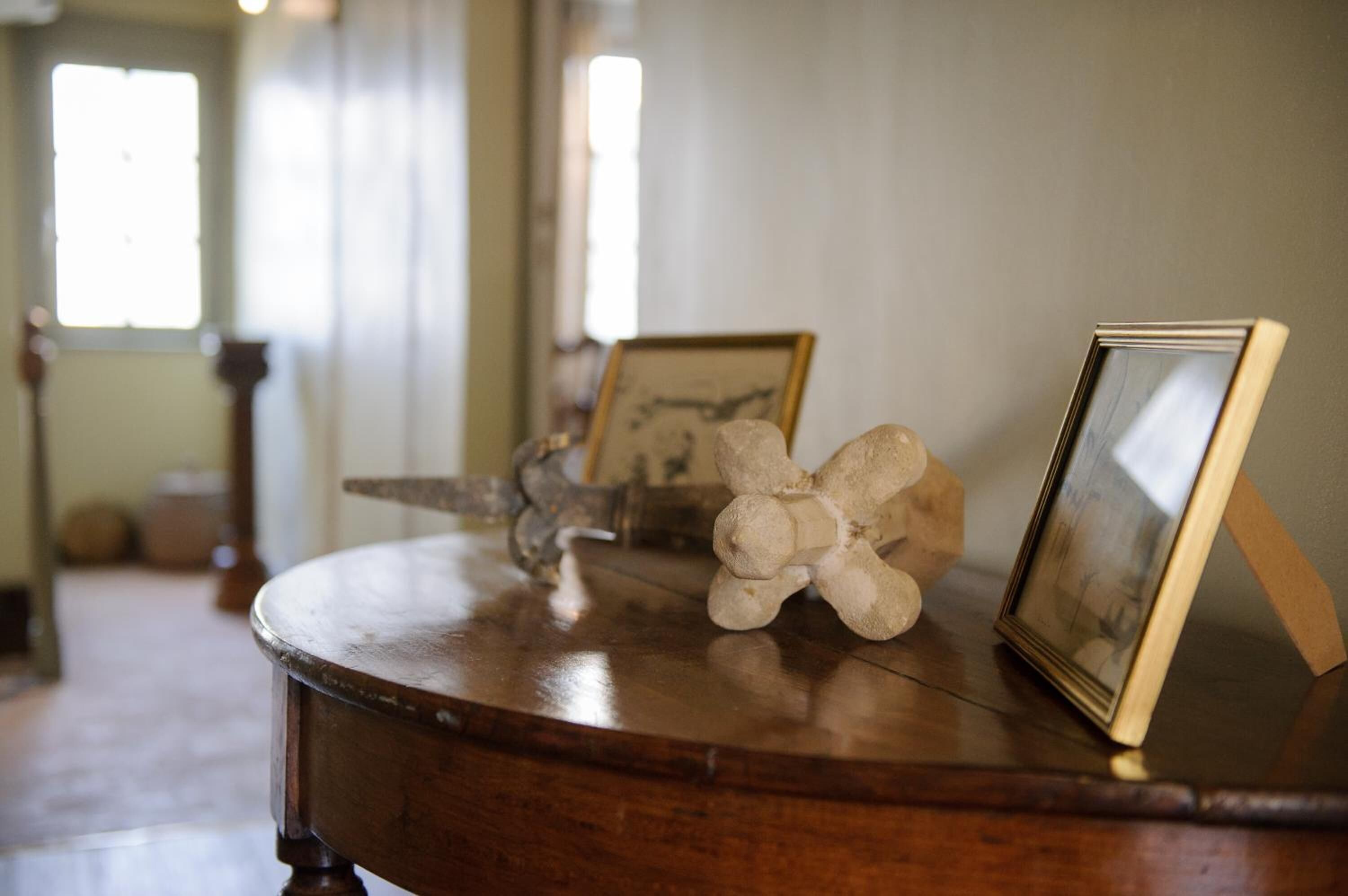 Una mesa de madera con un cuadro enmarco y una escultura.