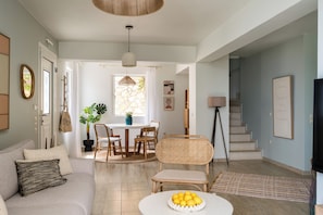 A living room with a sofa, coffee table, and a dining area with chairs and a table. - Villas Muscallas by Konnect, 200m from the Beach. (Paxos)