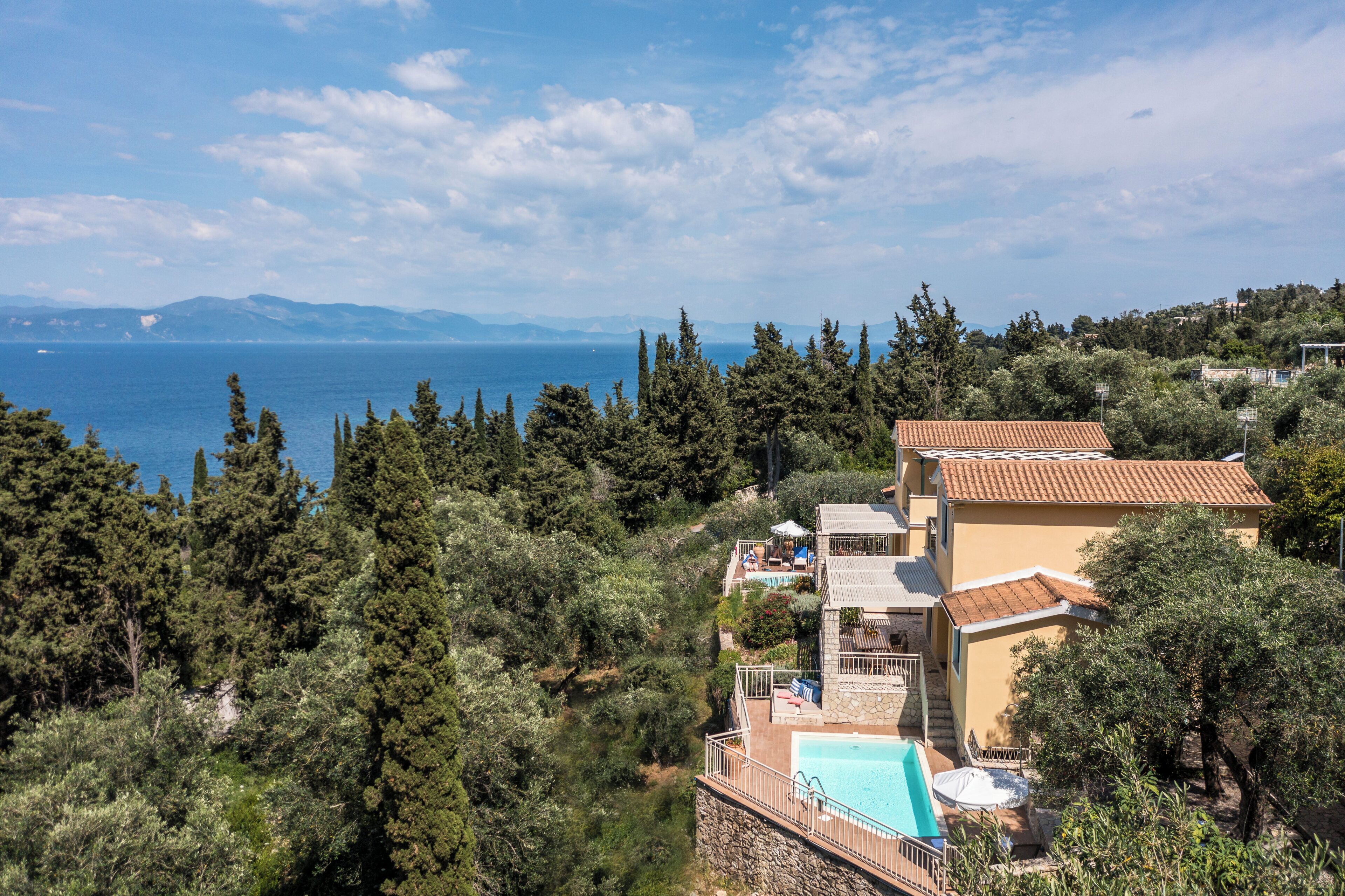 Eine Küstenvilla mit Pool, angelegtem Garten und Meerblick.