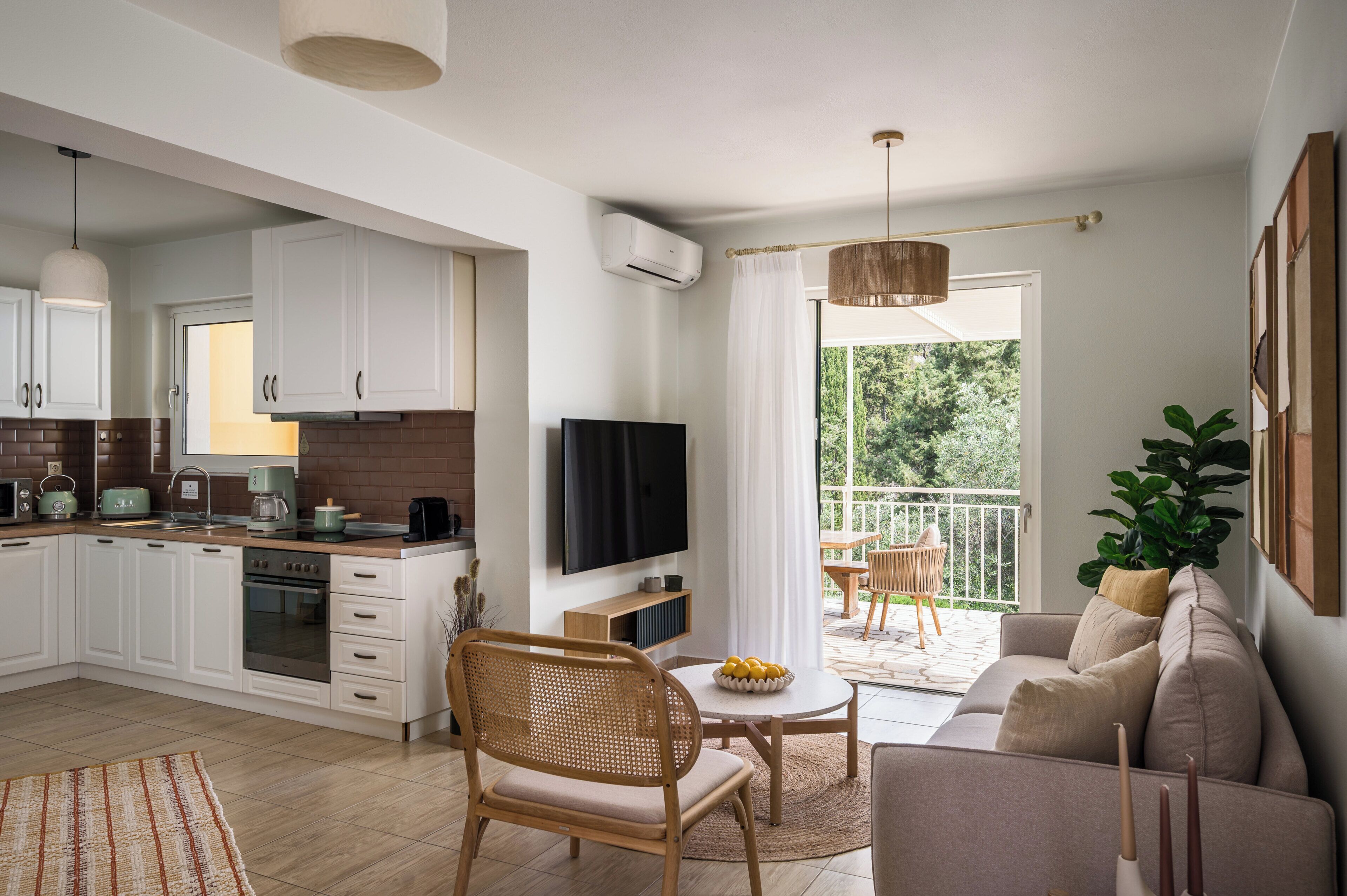 A modern kitchen with white cabinets, a flat-screen TV, and a dining area with a round table and chairs.