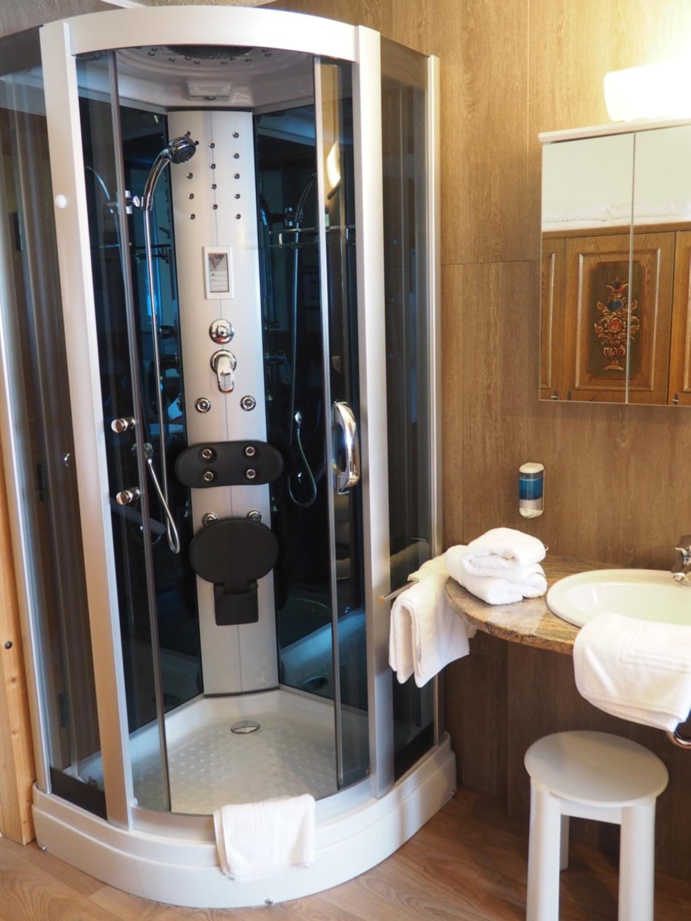 Un baño moderno con ducha envuelta en vidrio, lavamanos e inodoro.
