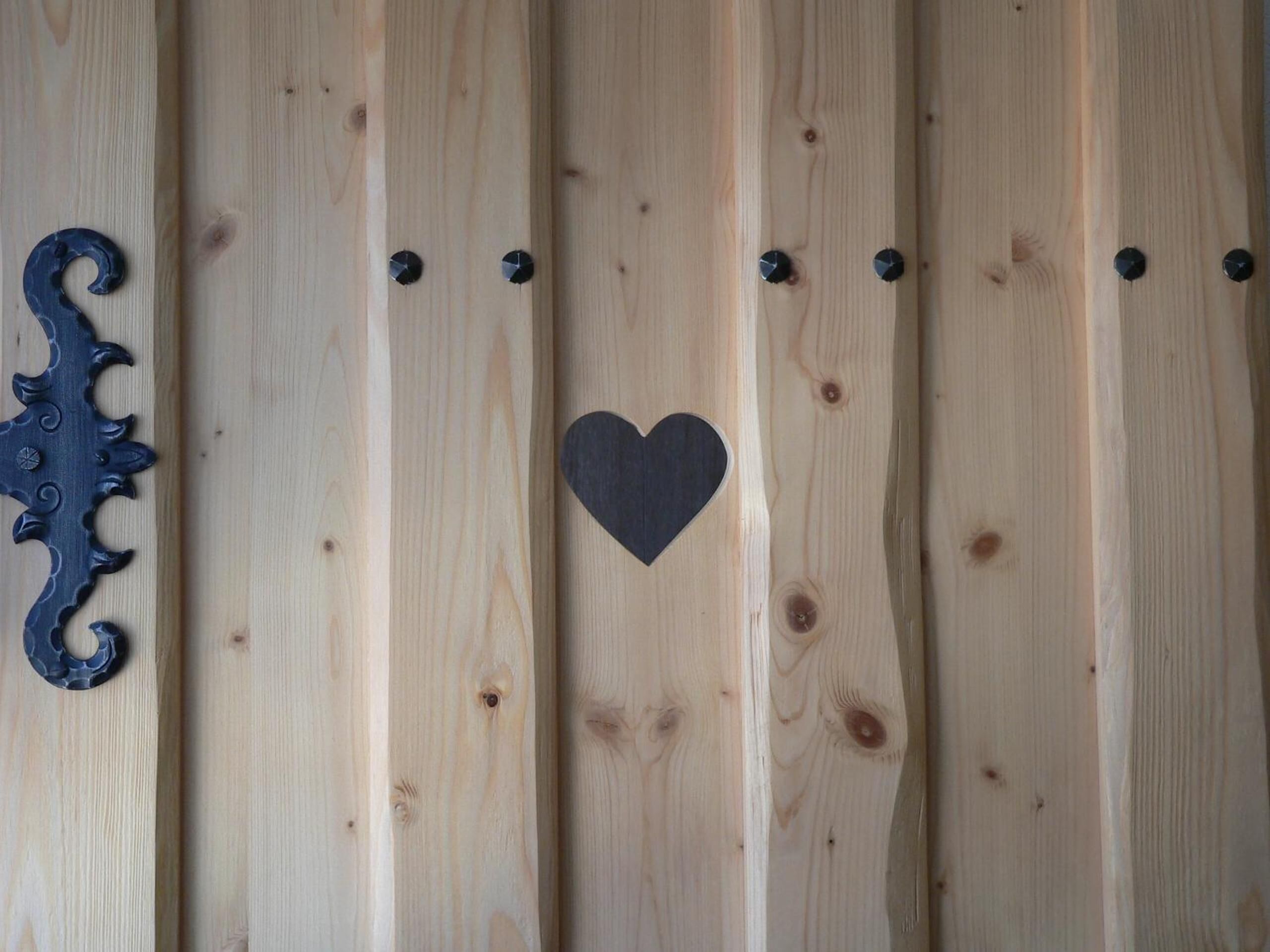 Una pared de madera con un adorno metálico y un recorte con forma de corazón.