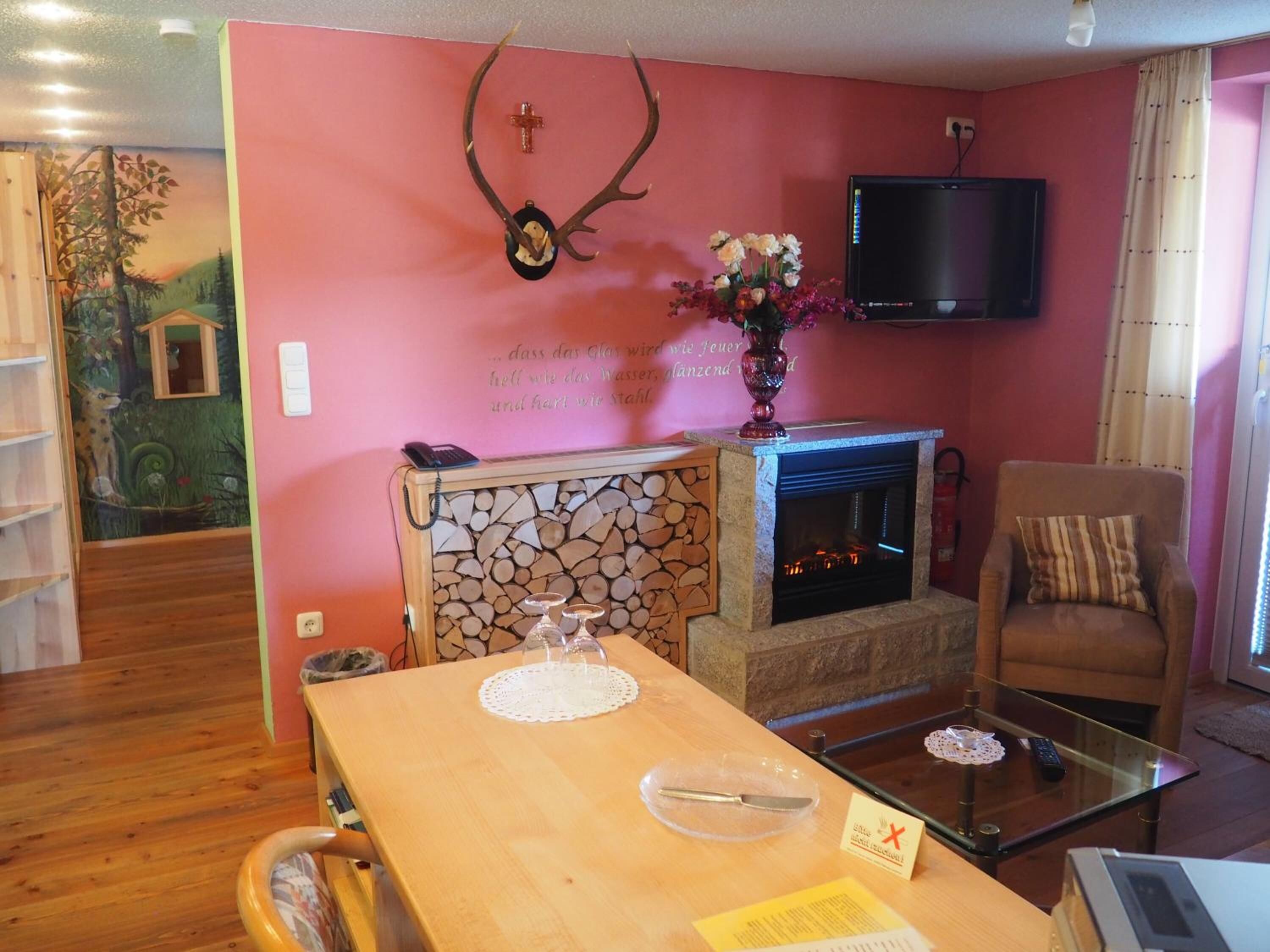 Una sala de estar con chimenea, televisor montado en la pared y un rincón de estar acogedor.