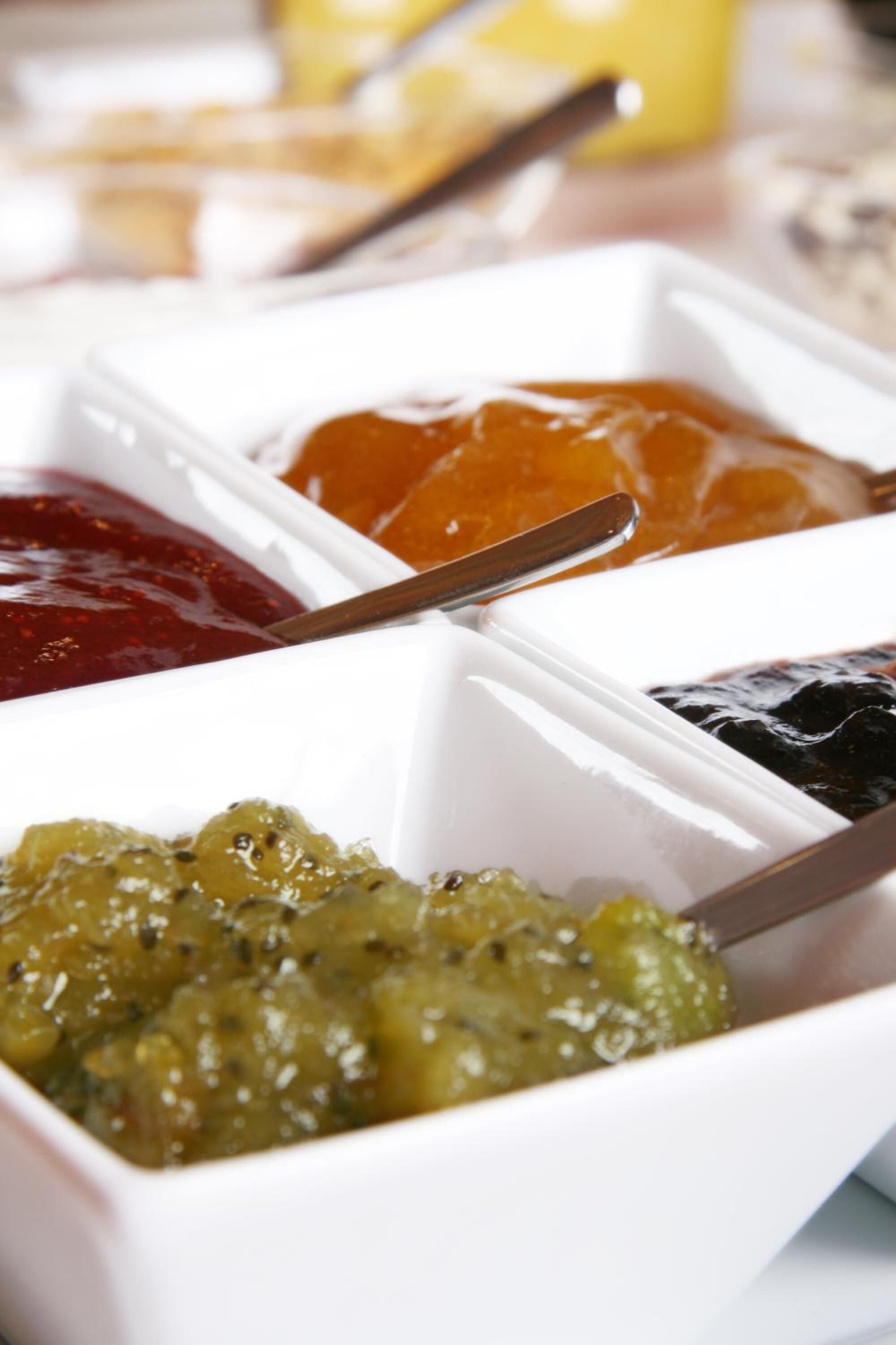 A close-up of four white containers with different colored sauces.