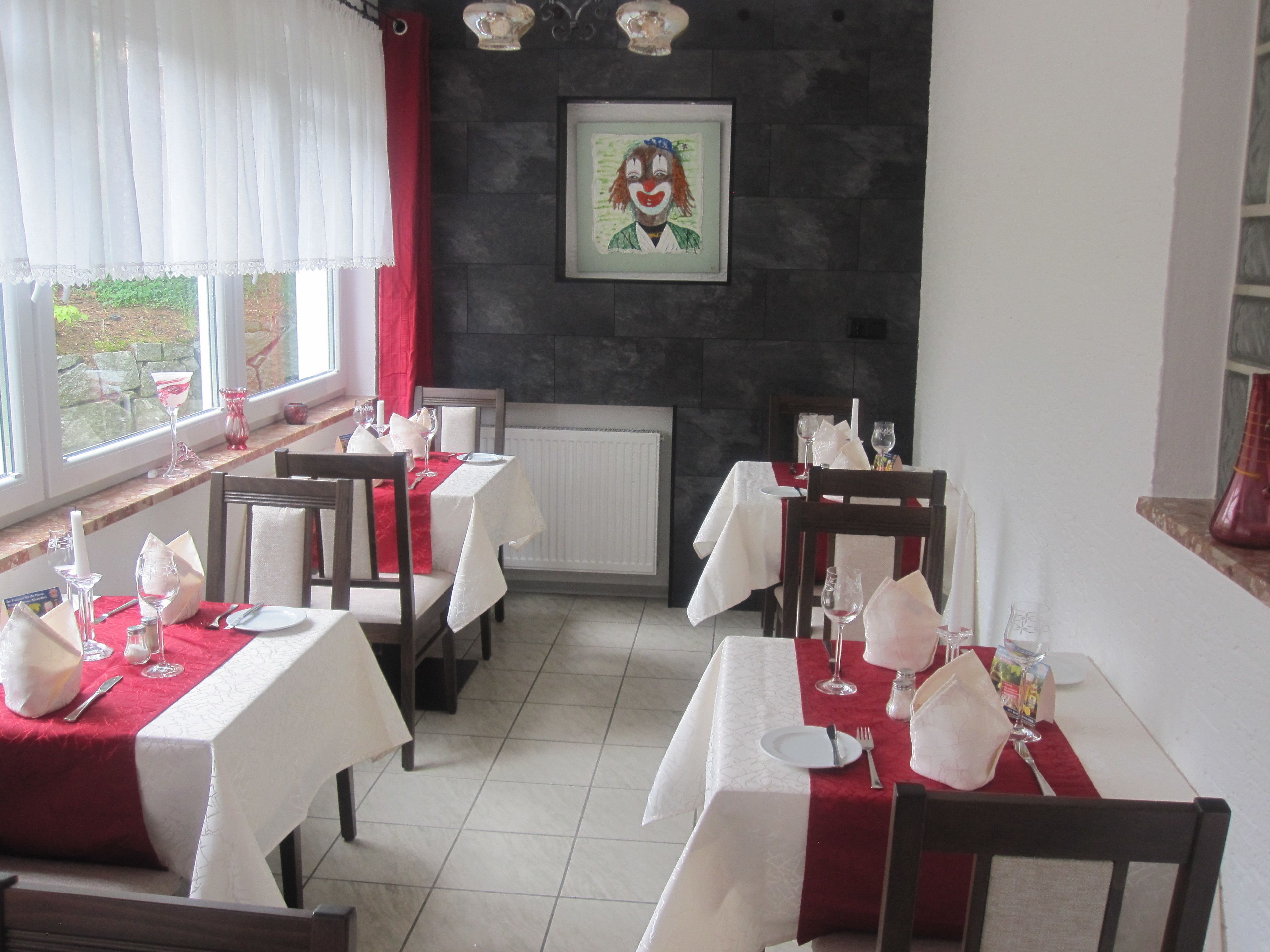 A restaurant with tables set for dining, a fireplace, and a painting on the wall.