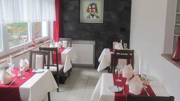 Ein Restaurant mit gedeckten Tischen, einem Kamin und einem Bild an der Wand.