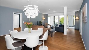 A modern living room with a round dining table, white chairs, a white chandelier, and a sofa. - Swiss Hotel Apartments-Interlaken (Interlaken)